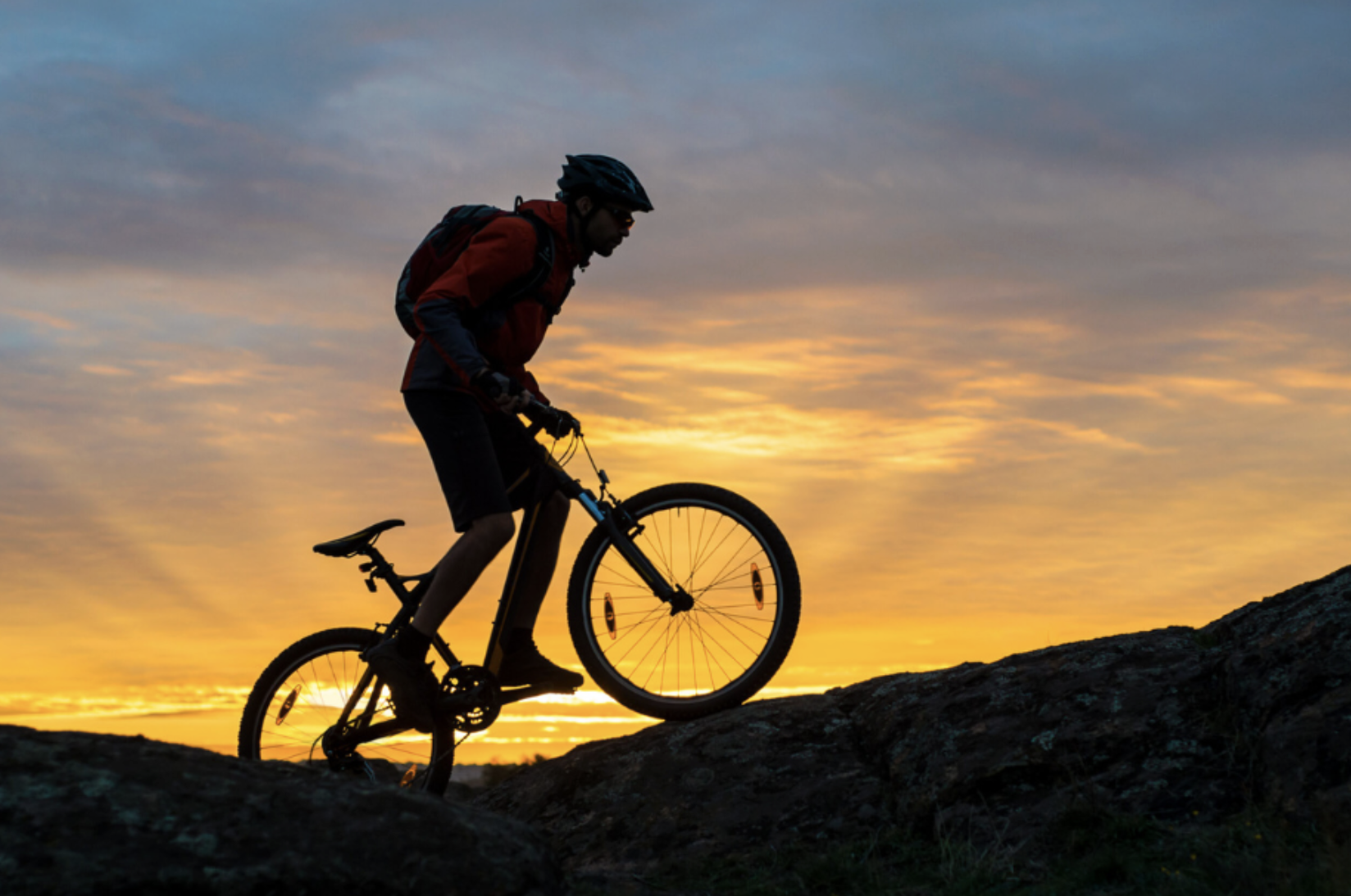 A cyclist climbing a hill at sunset, representing steady career progression