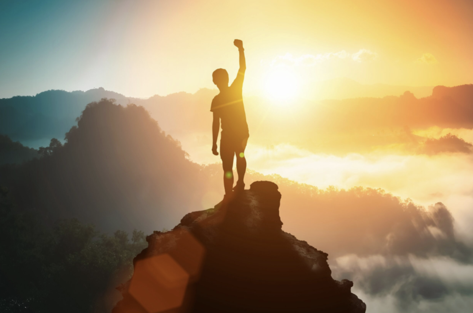 A person reaching a mountain summit at sunrise — representing opportunity and ambition at Andersen