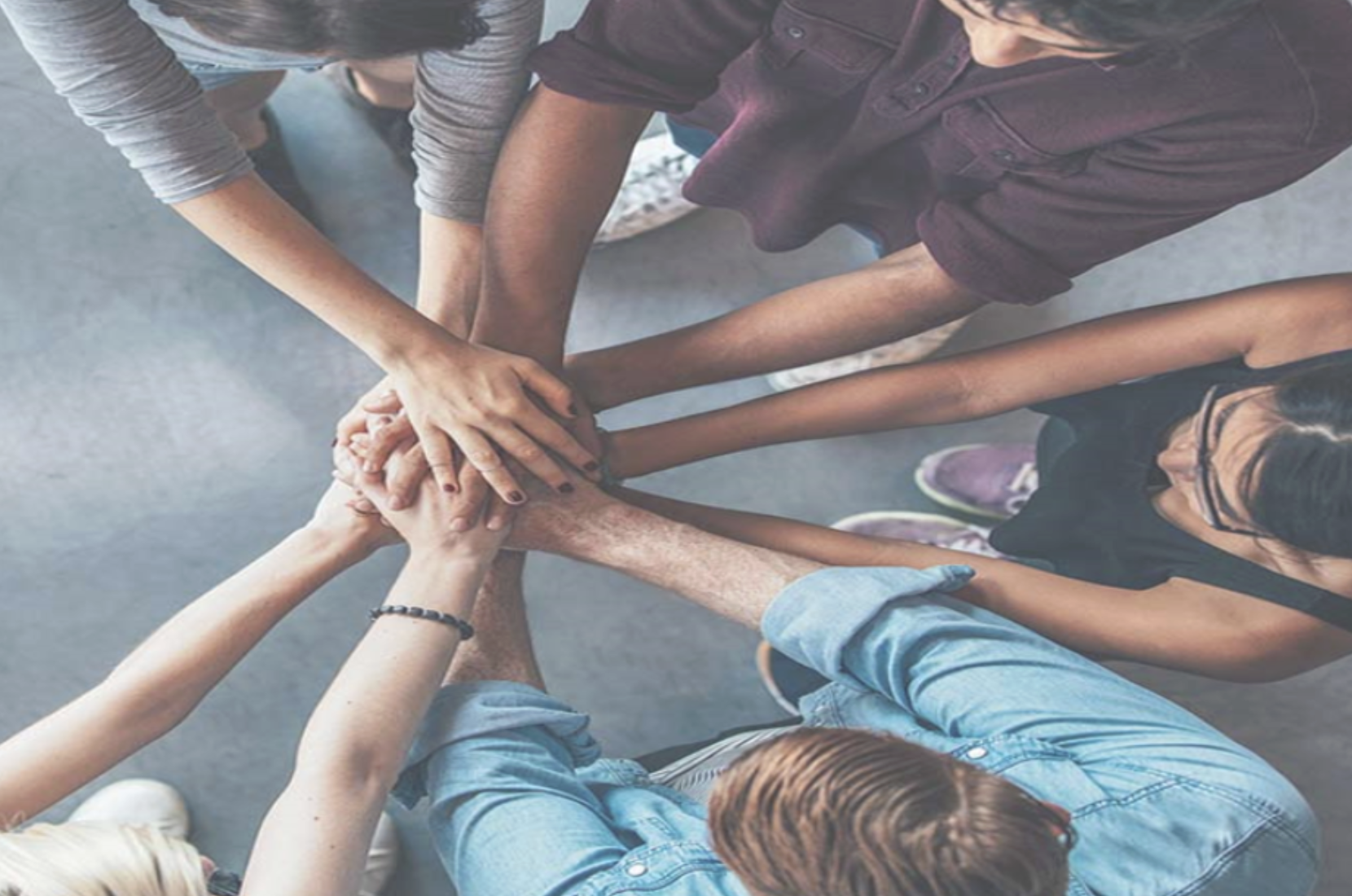 A group of people placing their hands together as a team