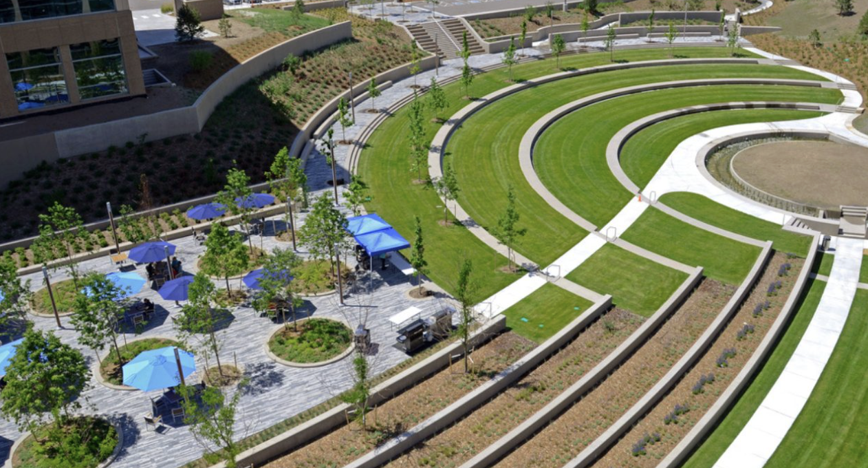 An aerial view of a large BrightView commercial landscape project with terraced lawns, trees and a shaded plaza