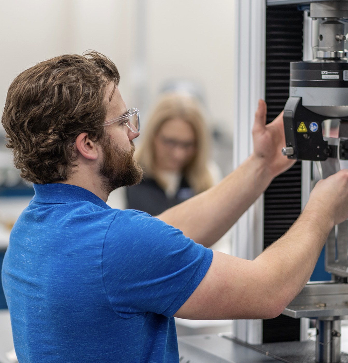A Carlisle Construction Materials employee operating a tensile-testing machine in the materials lab