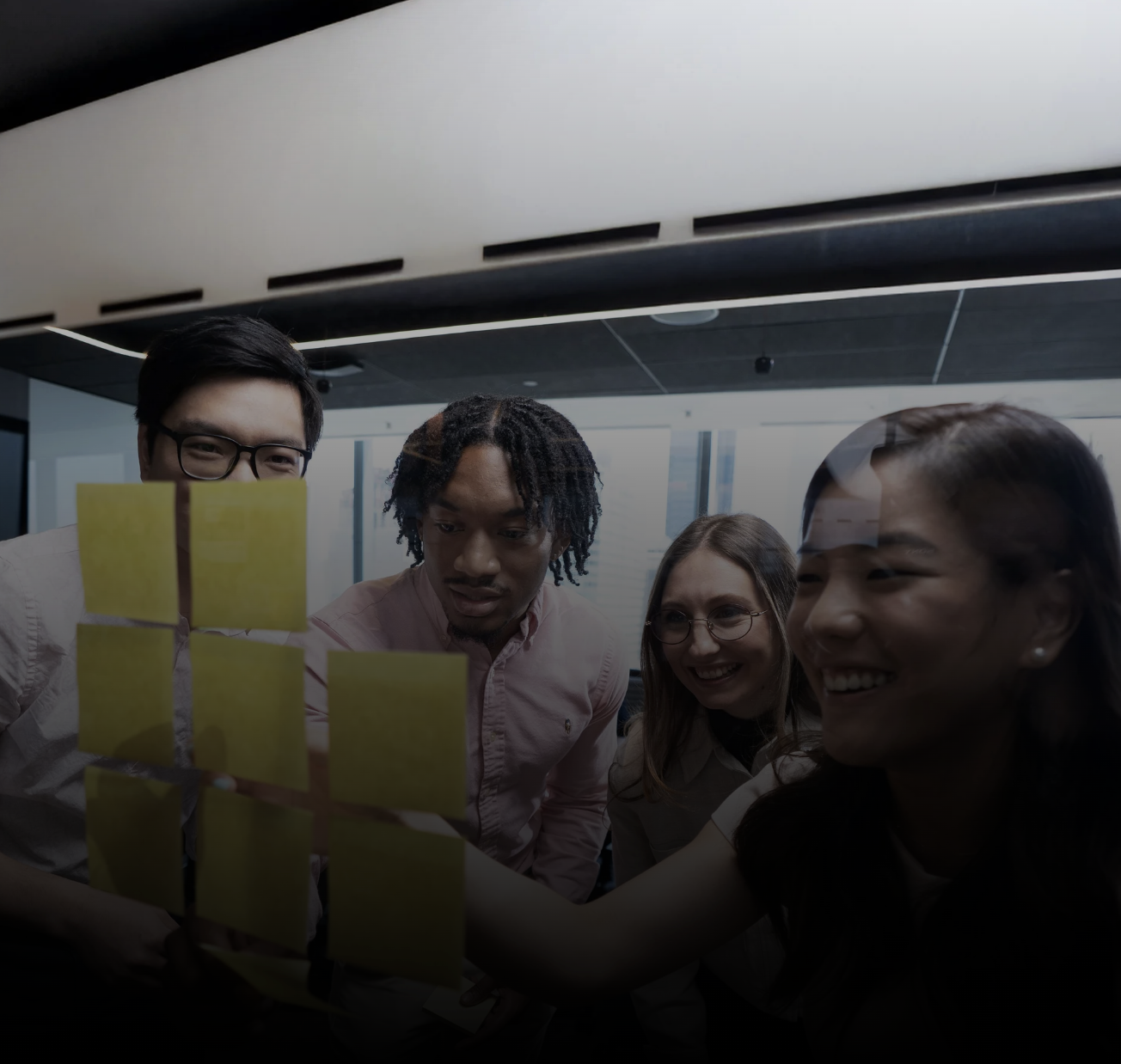 A diverse EY team collaborating with sticky notes on a glass wall