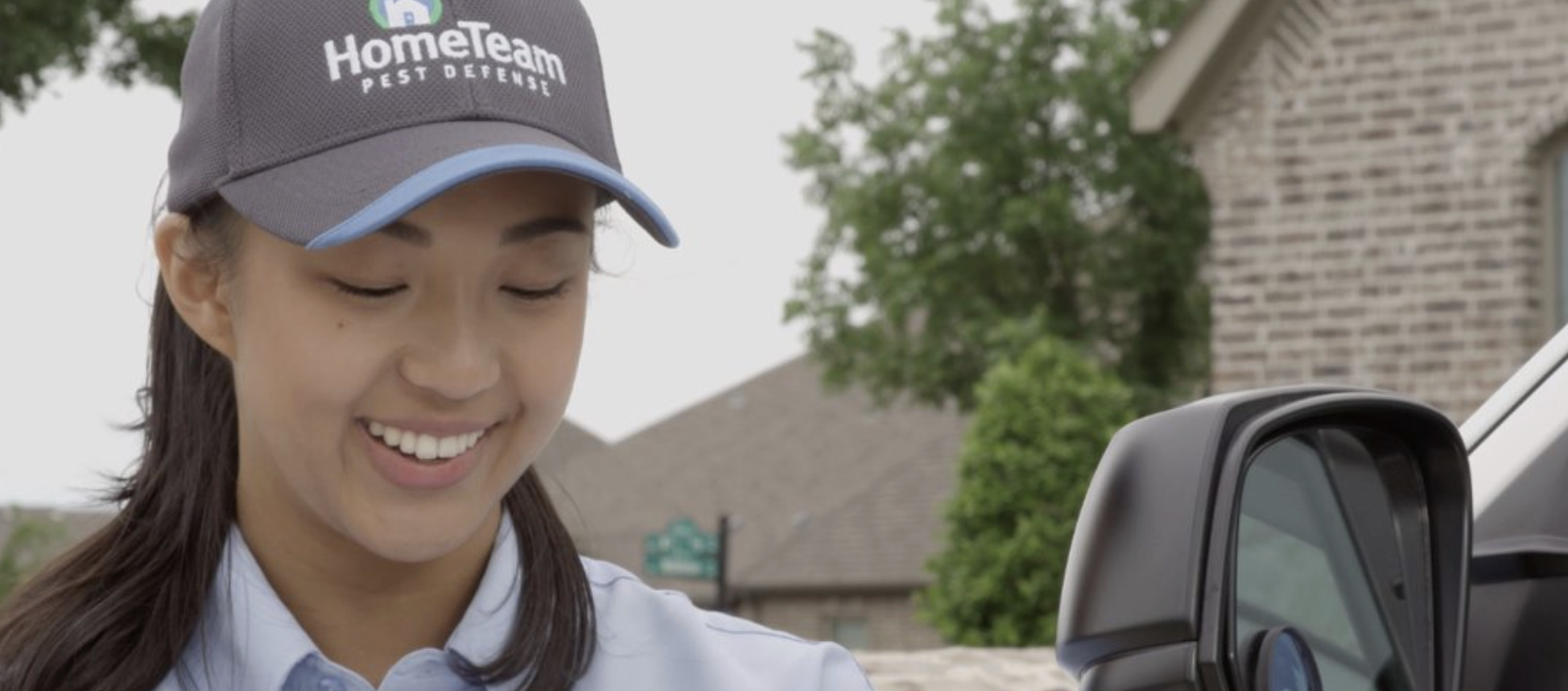 A smiling HomeTeam team member in uniform beside a service vehicle