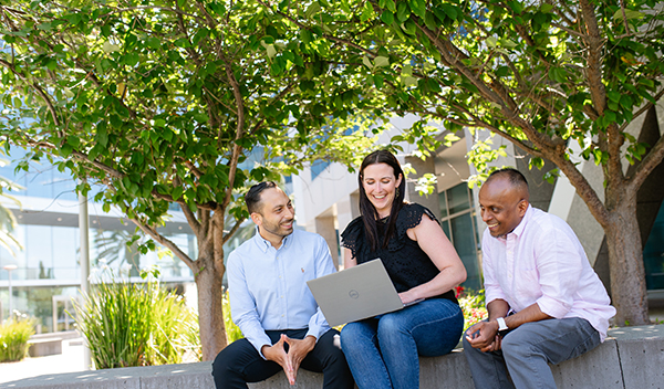 Three Marvell Technology colleagues collaborating on a laptop outdoors on the Santa Clara campus