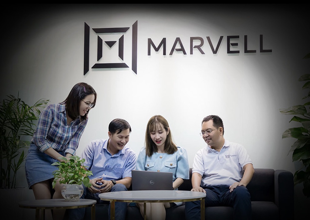 Marvell Technology employees gathered and smiling together in front of the Marvell logo