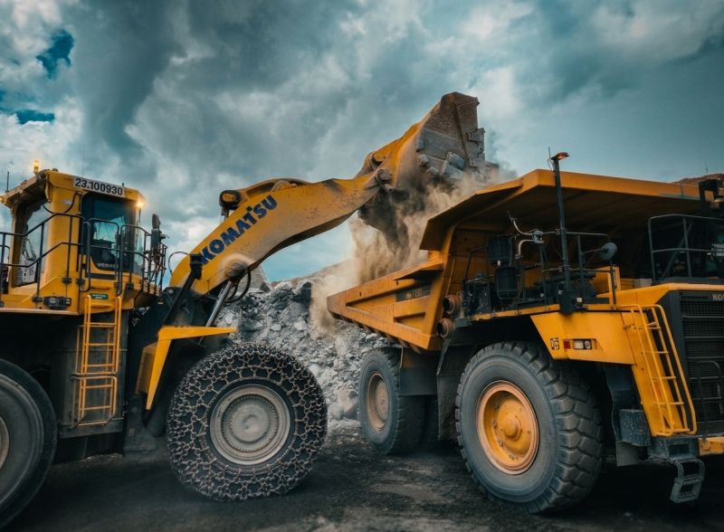 A wheel loader and haul truck moving crushed stone at a MidSouth Aggregates quarry under a dramatic sky