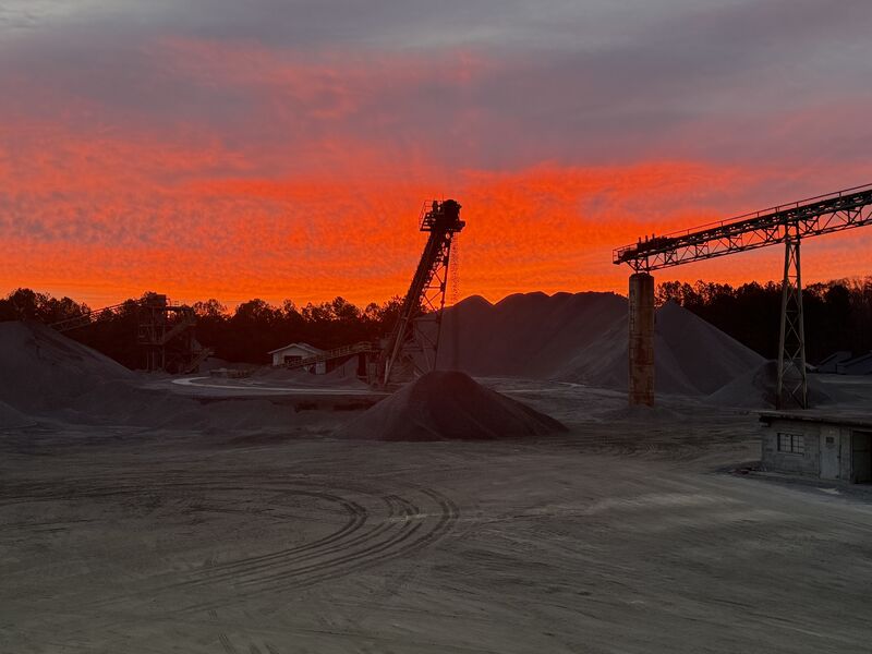 A MidSouth Aggregates quarry and processing plant silhouetted against a sunset sky