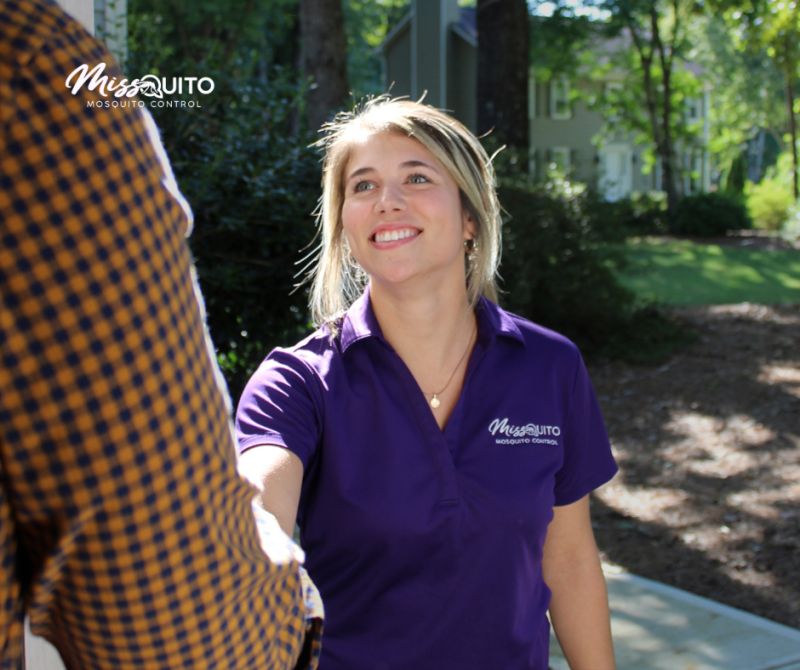 Smiling MissQuito team member greeting a customer outside their home
