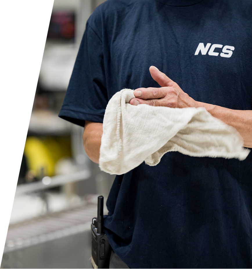 An NCS production team member in a branded shirt working on the carwash equipment manufacturing floor