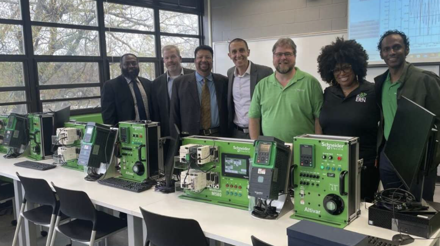 Schneider Electric team members beside control panels and automation equipment in a training lab