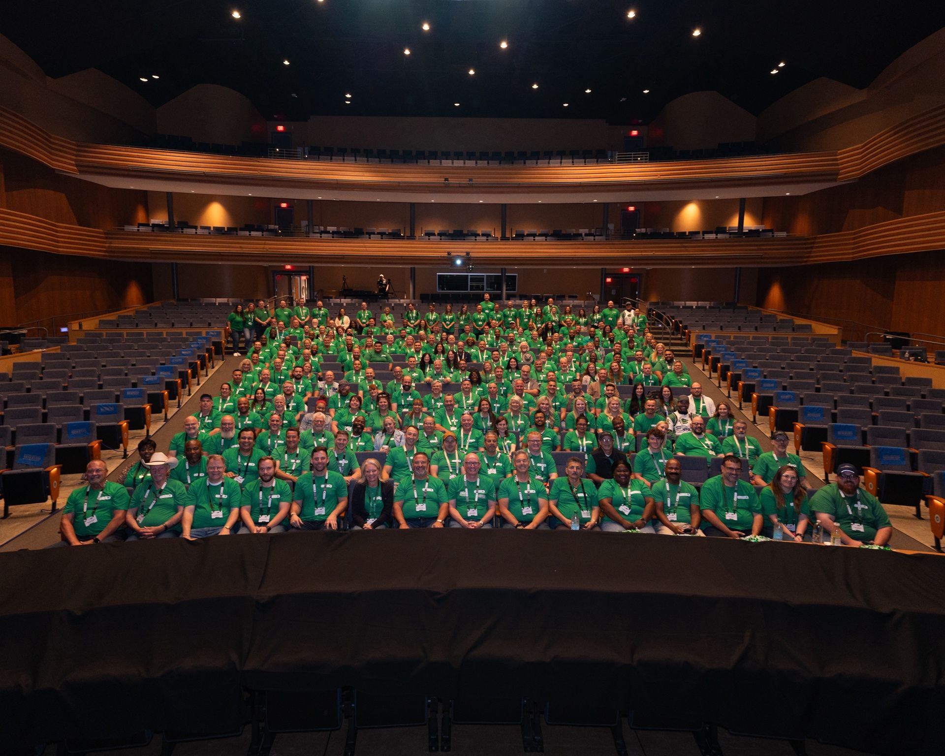 Hundreds of SSC team members in green shirts gathered in a theater for the company's annual conference
