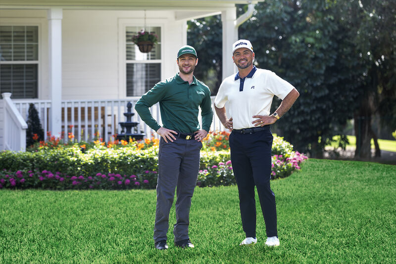 A TruGreen lawn care specialist and a customer standing together on a healthy green lawn in front of a home