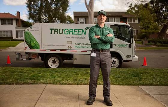A TruGreen lawn care specialist standing in front of a branded TruGreen service truck