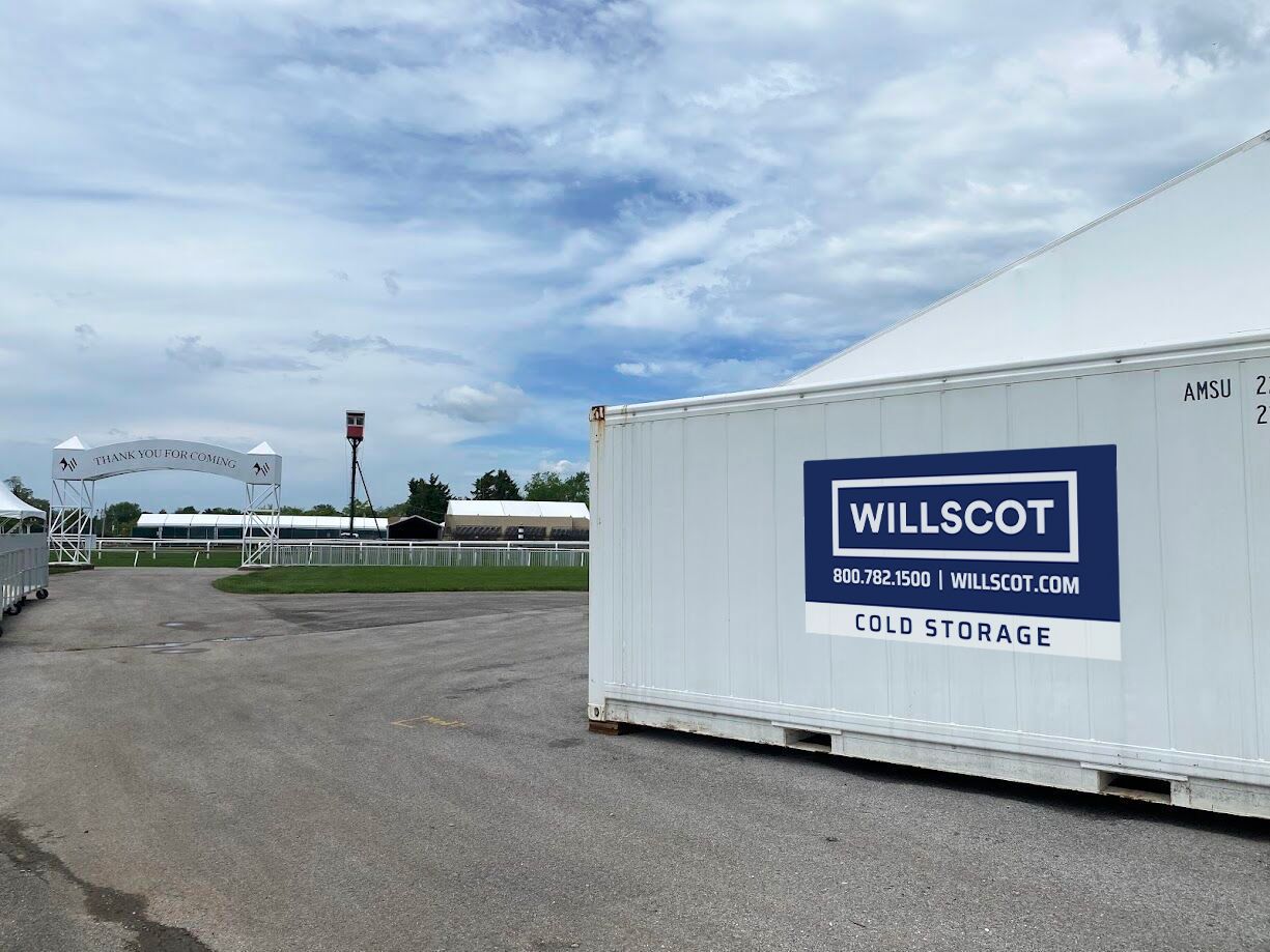 A WillScot-branded portable storage container in a branch yard under a bright sky