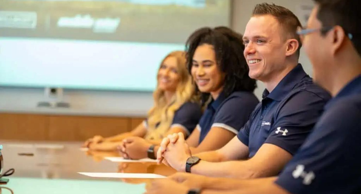 WillScot team members smiling during a learning and development session around a conference table