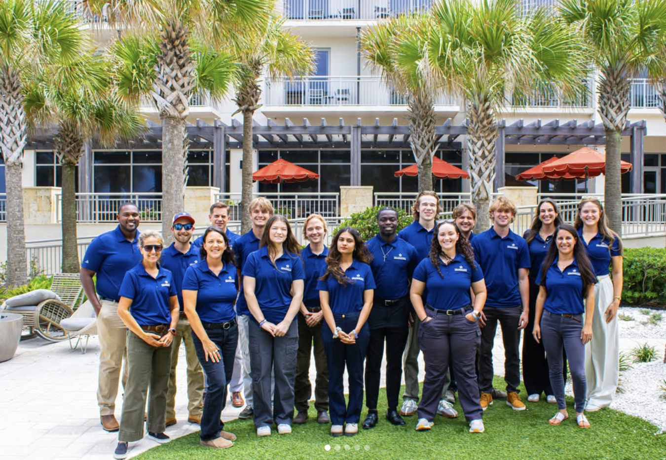 Yellowstone Landscape summer interns in navy polo shirts gathered together at a beachfront resort property