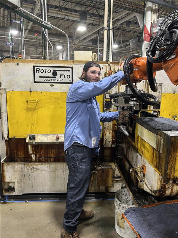 A man operates machinery in the Harley-Davidson factory, focused on his task amidst industrial surroundings.