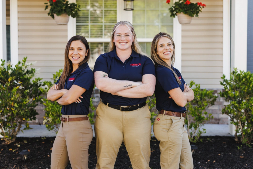 Three women Trutech employees standing back to back with arms crossed and smiling confidently